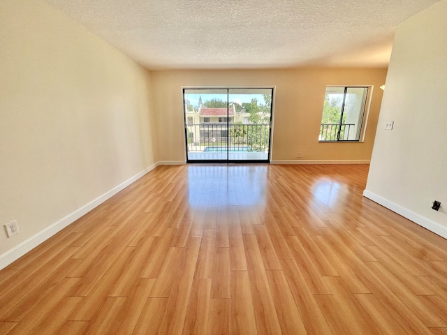 unfurnished room with a textured ceiling and light hardwood / wood-style flooring