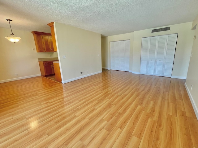 unfurnished living room with a textured ceiling and light hardwood / wood-style flooring