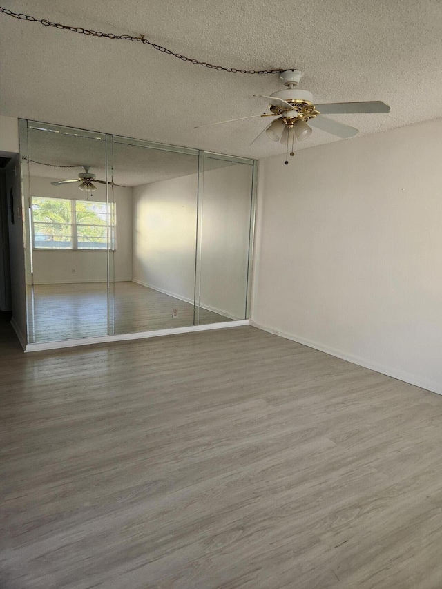 unfurnished bedroom with ceiling fan, wood-type flooring, a textured ceiling, and a closet