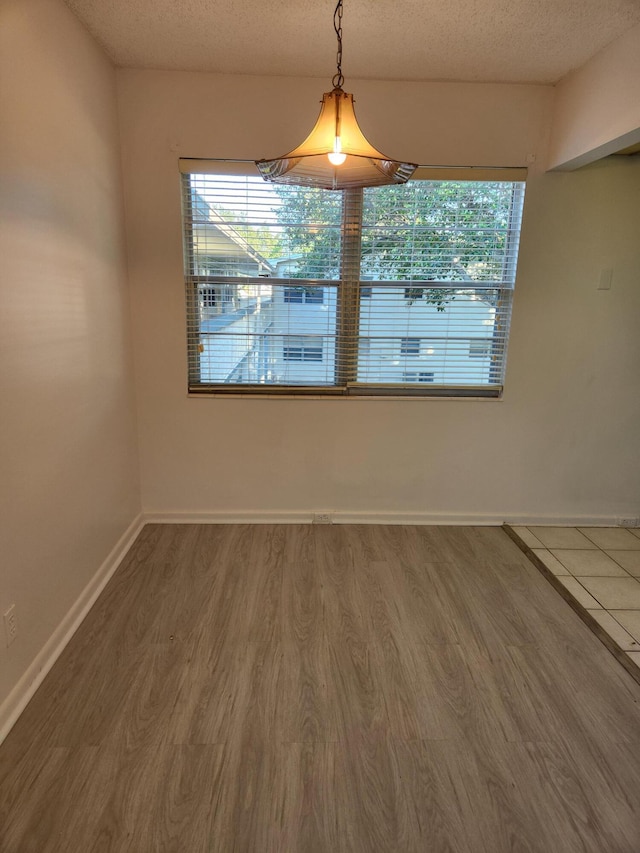 unfurnished dining area with a textured ceiling, hardwood / wood-style flooring, and a wealth of natural light