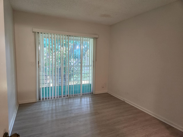 unfurnished room featuring hardwood / wood-style flooring and a textured ceiling