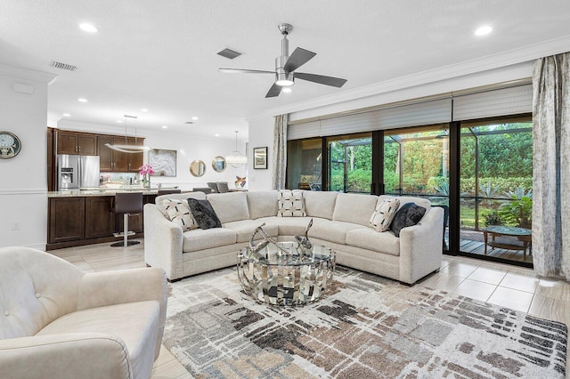 living room with a textured ceiling, ceiling fan, light tile patterned flooring, and crown molding