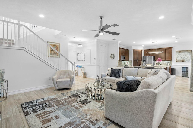 living room with ceiling fan, beverage cooler, and ornamental molding