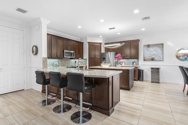 kitchen with appliances with stainless steel finishes, tasteful backsplash, a breakfast bar, sink, and pendant lighting