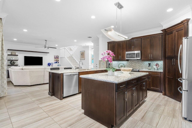 kitchen with appliances with stainless steel finishes, a kitchen island, pendant lighting, and sink