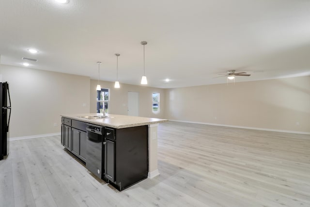 kitchen featuring black appliances, sink, light hardwood / wood-style flooring, an island with sink, and decorative light fixtures