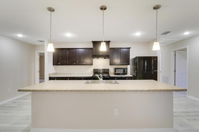 kitchen with black appliances, light hardwood / wood-style floors, a center island with sink, and sink