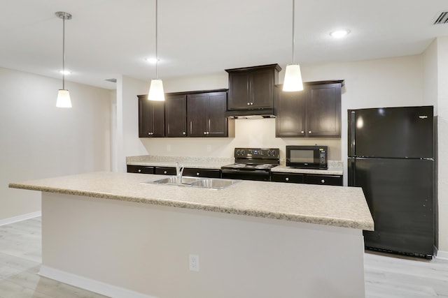 kitchen featuring black appliances, light hardwood / wood-style floors, sink, and an island with sink