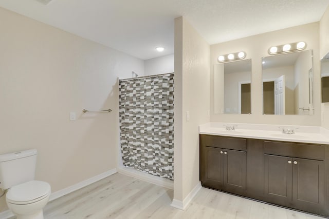 bathroom with a shower, hardwood / wood-style floors, vanity, and toilet