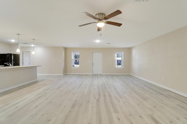 unfurnished living room featuring ceiling fan and light wood-type flooring