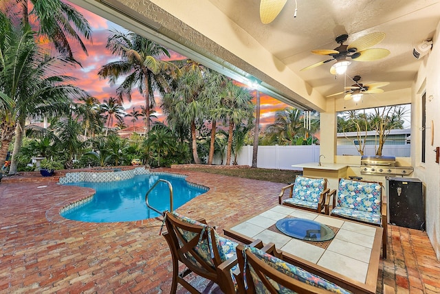 pool at dusk with area for grilling, ceiling fan, and a patio area