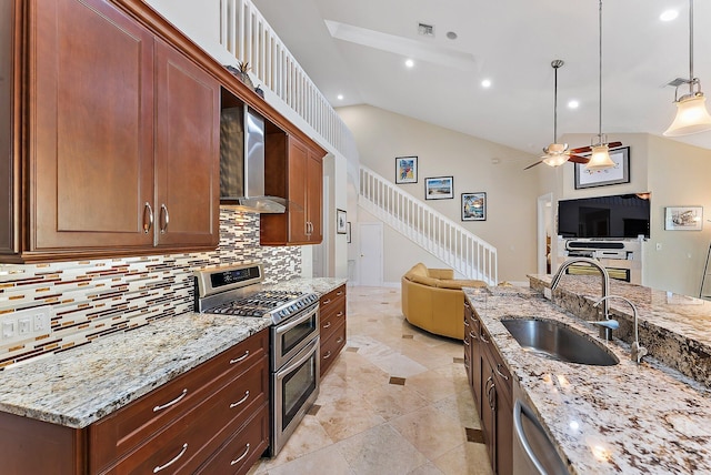 kitchen with ceiling fan, sink, wall chimney exhaust hood, light stone counters, and appliances with stainless steel finishes