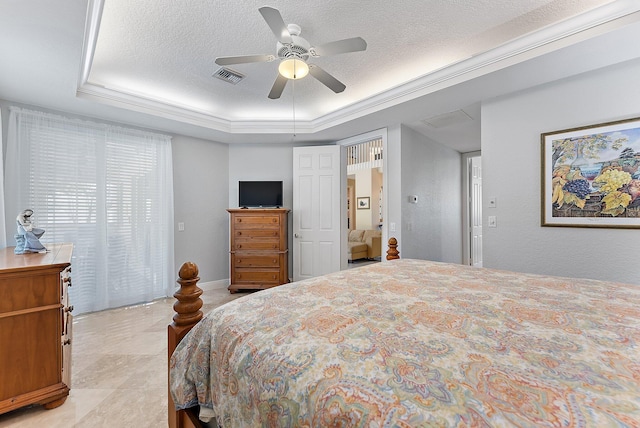 bedroom with a textured ceiling, a tray ceiling, and ceiling fan