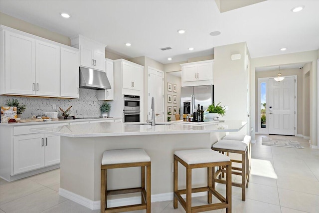 kitchen featuring an island with sink, white cabinets, and stainless steel appliances