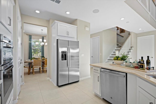 kitchen featuring a notable chandelier, white cabinets, light tile patterned floors, decorative light fixtures, and stainless steel appliances