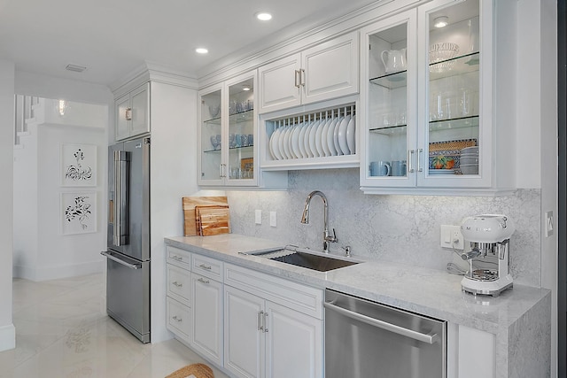 kitchen with light stone countertops, backsplash, stainless steel appliances, sink, and white cabinets