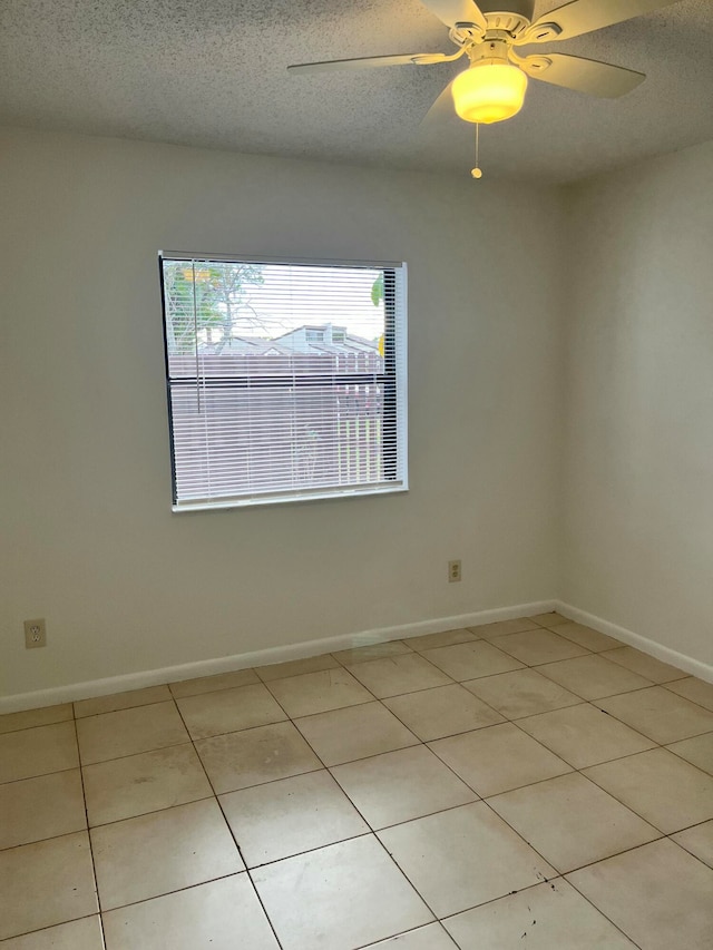 tiled empty room featuring a textured ceiling