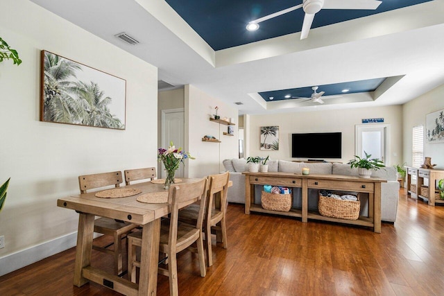 dining space featuring dark hardwood / wood-style floors, a raised ceiling, and ceiling fan