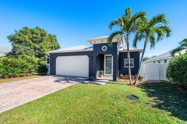 view of front of home with decorative driveway, stucco siding, a front yard, fence, and a garage