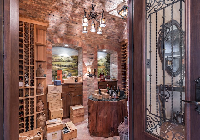 wine area with brick ceiling, brick wall, lofted ceiling, and an inviting chandelier