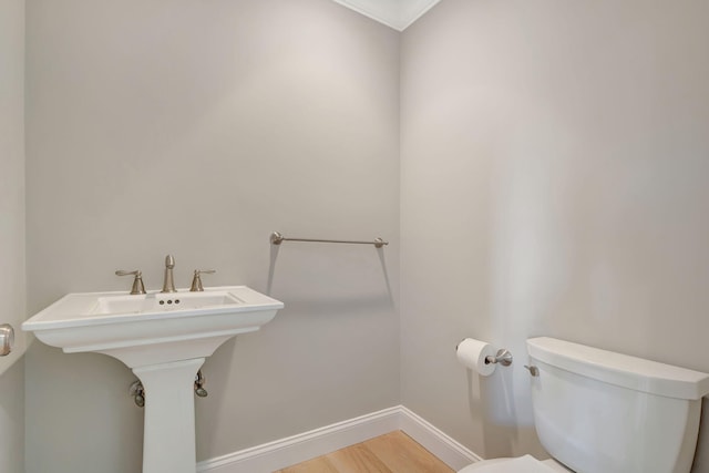 bathroom featuring hardwood / wood-style flooring, toilet, crown molding, and sink