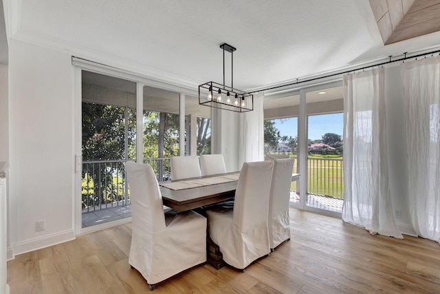 dining space featuring a textured ceiling, light hardwood / wood-style flooring, crown molding, and a notable chandelier