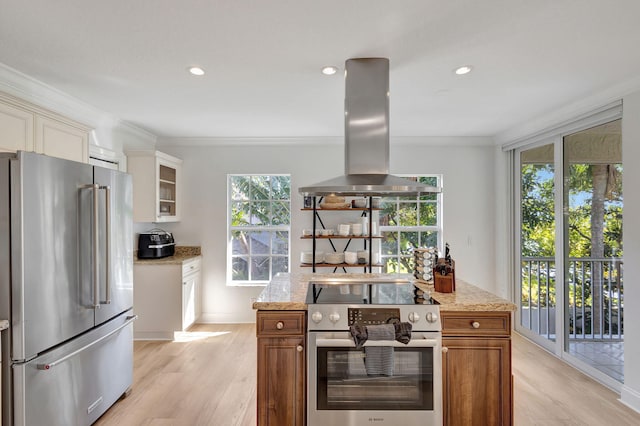 kitchen featuring light stone countertops, stainless steel appliances, island range hood, crown molding, and light hardwood / wood-style flooring