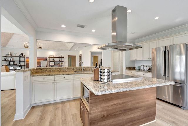 kitchen featuring island exhaust hood, appliances with stainless steel finishes, sink, light hardwood / wood-style flooring, and a kitchen island