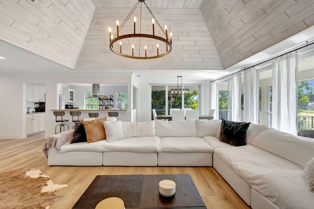 living room featuring an inviting chandelier, light hardwood / wood-style floors, and high vaulted ceiling