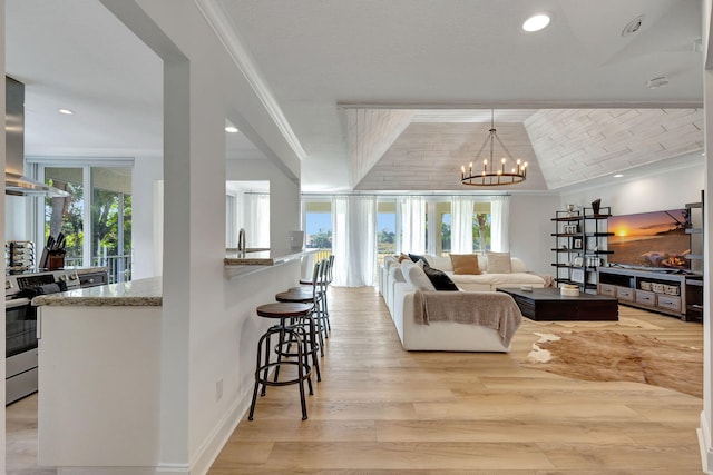 living room featuring a chandelier, light hardwood / wood-style floors, a wealth of natural light, and ornamental molding