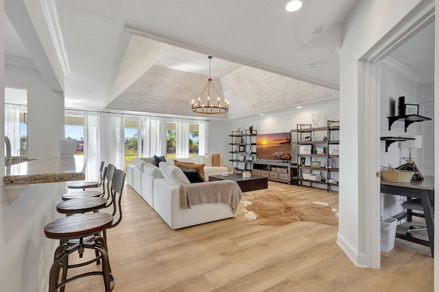 living room with light wood-type flooring, crown molding, and a chandelier