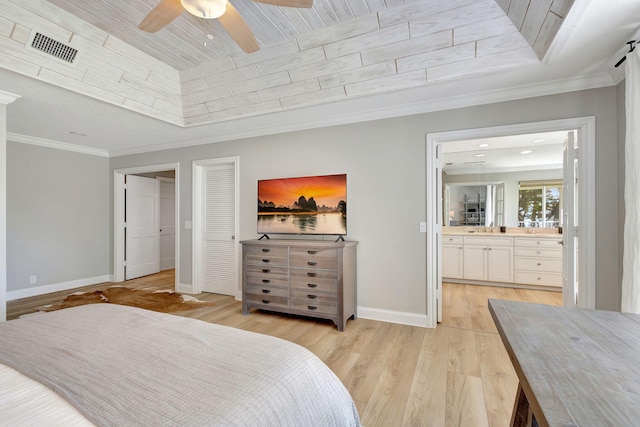 bedroom with ceiling fan, ensuite bathroom, light wood-type flooring, a tray ceiling, and ornamental molding