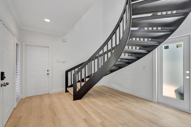 foyer entrance with light hardwood / wood-style floors and ornamental molding