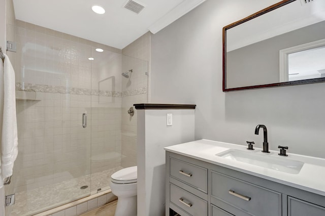 bathroom featuring vanity, toilet, ornamental molding, and a shower with door