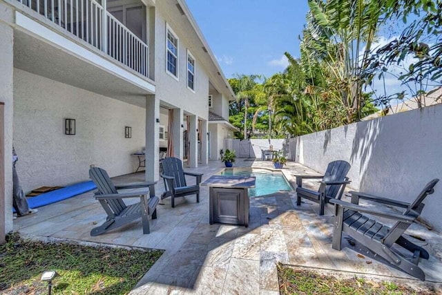 view of patio with a fenced in pool and a balcony