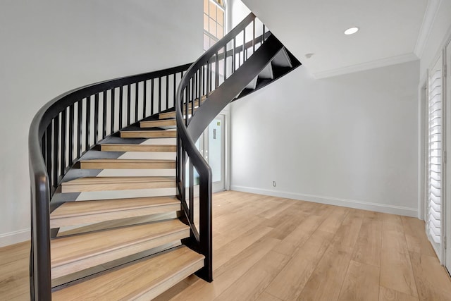 staircase featuring hardwood / wood-style floors and ornamental molding