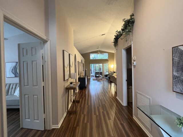 hallway with dark hardwood / wood-style flooring and vaulted ceiling