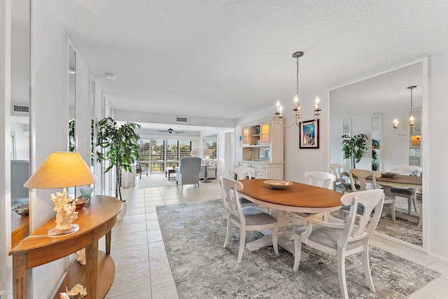 tiled dining area with ceiling fan with notable chandelier and a textured ceiling