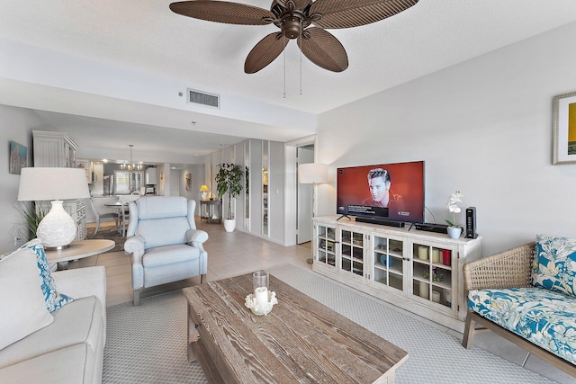 living room featuring a textured ceiling, light carpet, and ceiling fan with notable chandelier