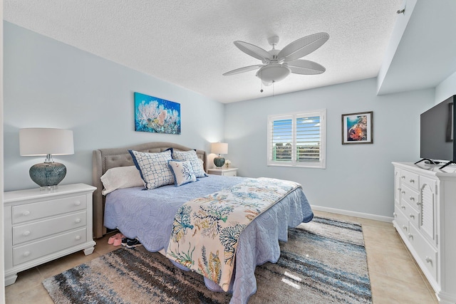 bedroom with ceiling fan, light tile patterned floors, and a textured ceiling