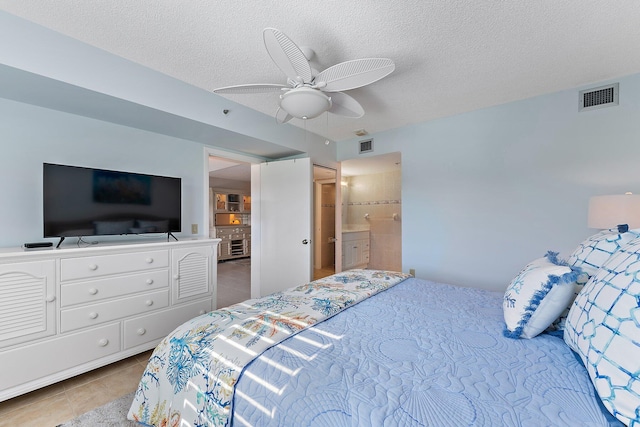 bedroom featuring ceiling fan, light tile patterned floors, ensuite bathroom, and a textured ceiling