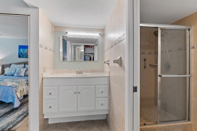 bathroom featuring an enclosed shower, vanity, tile patterned floors, and tile walls