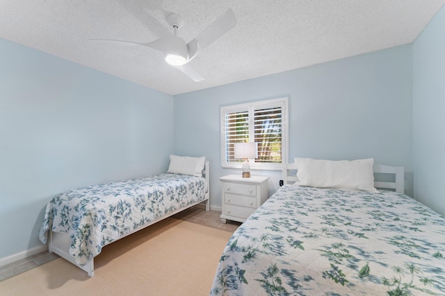 bedroom featuring ceiling fan, light tile patterned floors, and a textured ceiling