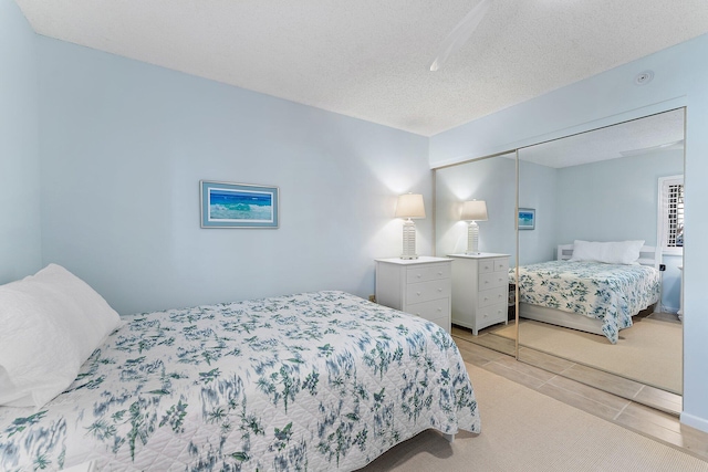 bedroom featuring a closet, light colored carpet, and a textured ceiling