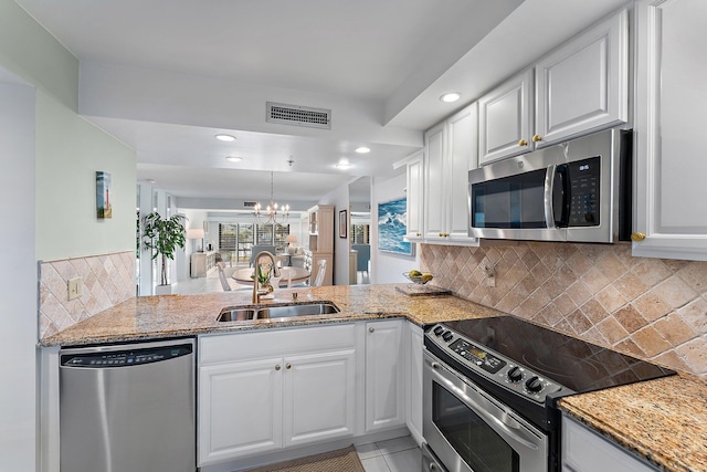 kitchen with sink, appliances with stainless steel finishes, white cabinetry, kitchen peninsula, and a chandelier