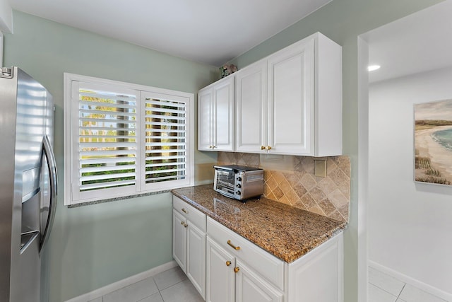 kitchen featuring dark stone countertops, stainless steel fridge with ice dispenser, white cabinets, and light tile patterned floors