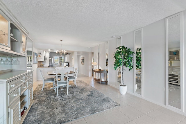 dining space featuring light tile patterned floors, a textured ceiling, and an inviting chandelier