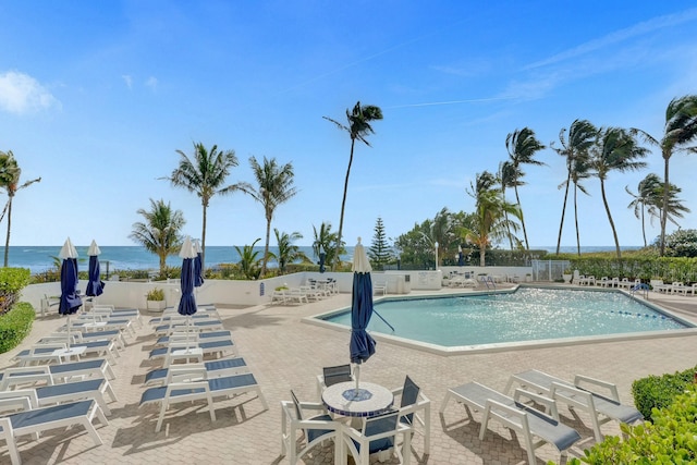 view of pool featuring a water view and a patio area