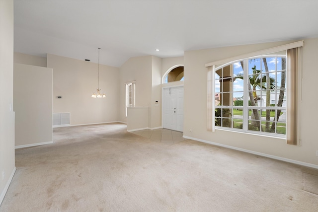 carpeted empty room with lofted ceiling and an inviting chandelier