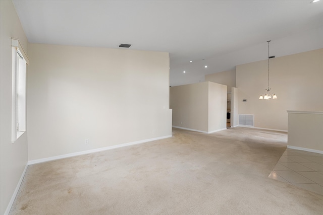 spare room featuring light carpet and an inviting chandelier